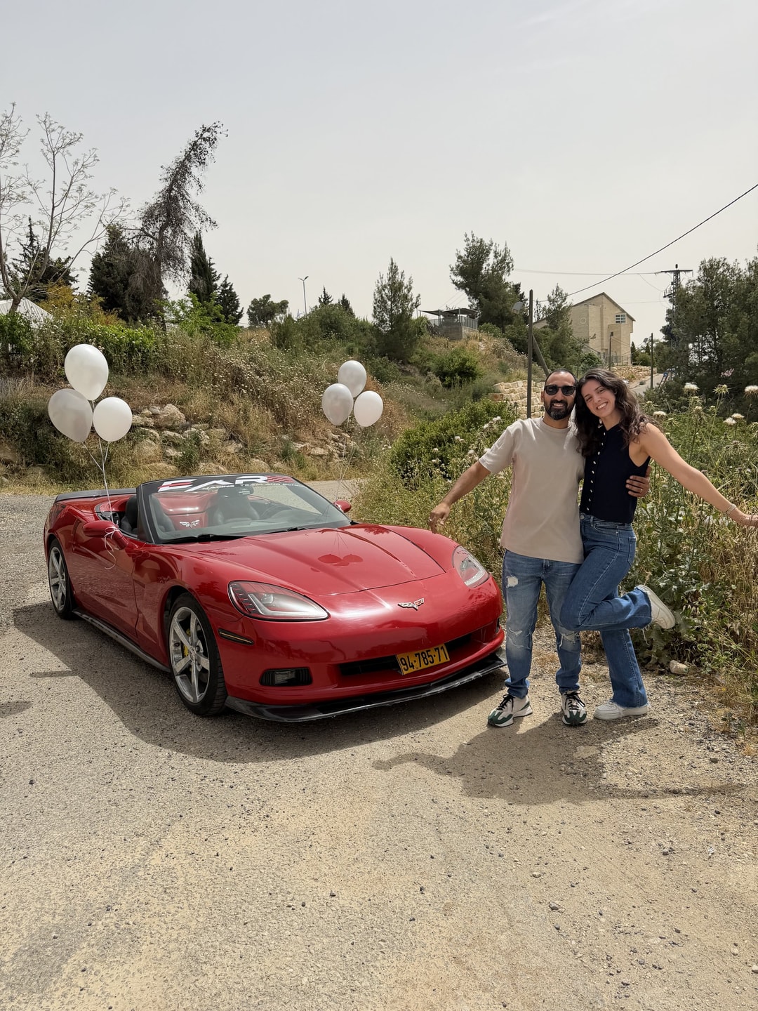 זוג מצטלם ליד קורבט אדומה עם בלונים לבנים, בהרי יהודה