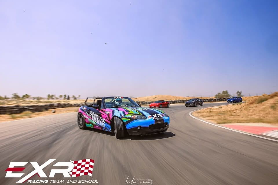 רכב הדריפט הצבעוני של EXR מוביל שיירת רכבים בפנייה במסלול